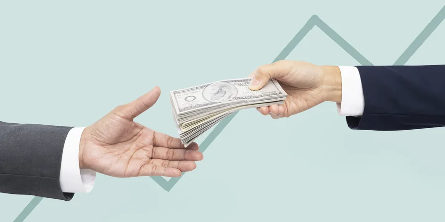 One hand passing a stack of cash to another outstretched hand, against a growth-chart background